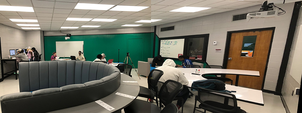 image of tech zone Panoramic view of a modern study room with students working at various stations. The room features a large, semi-circular seating area in the center, students using computers on the left, and others working on laptops and whiteboards on the right. The walls are painted green and gray, with ample overhead lighting.